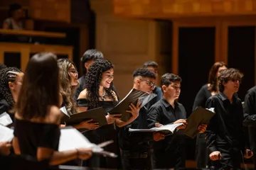 Os jovens do Coro estão segurando partituras e vestindo preto.
