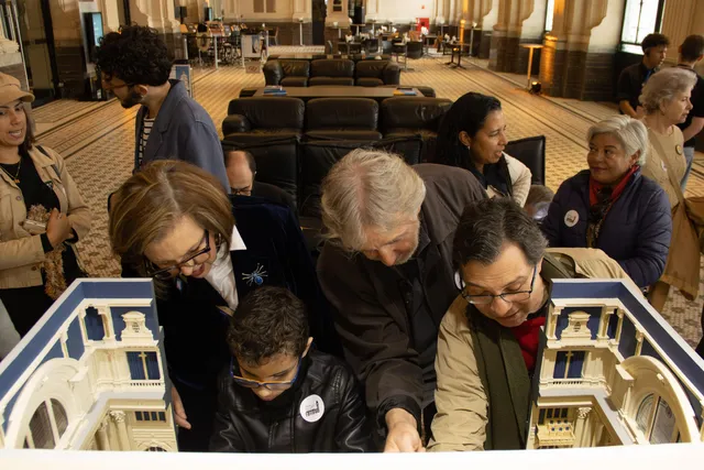 Three people are handling the tactile model of Sala São Paulo.