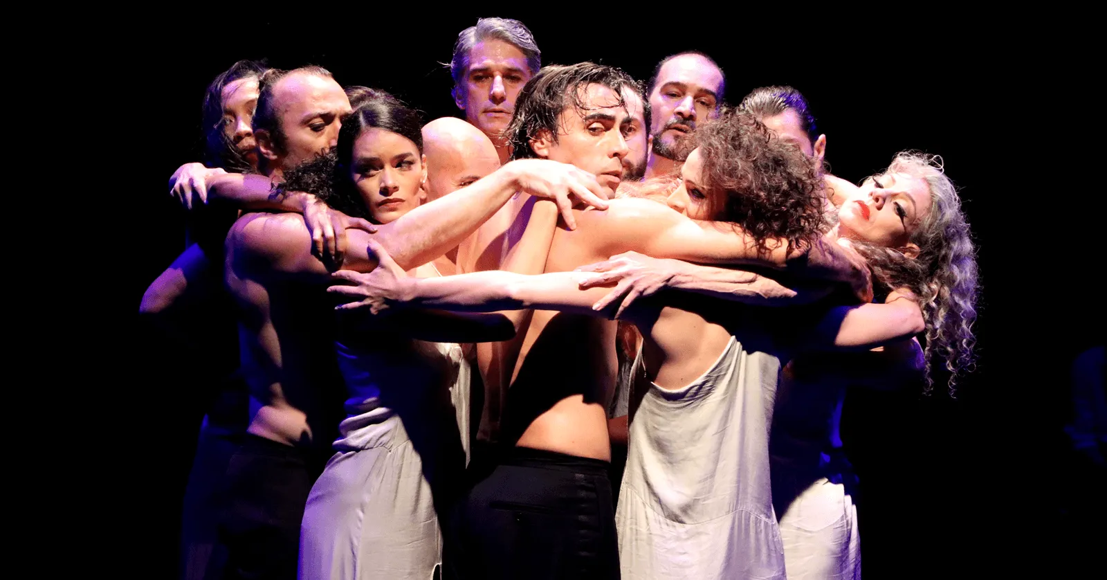 Foto de grupo de bailarinos abraçados durante espetáculo.