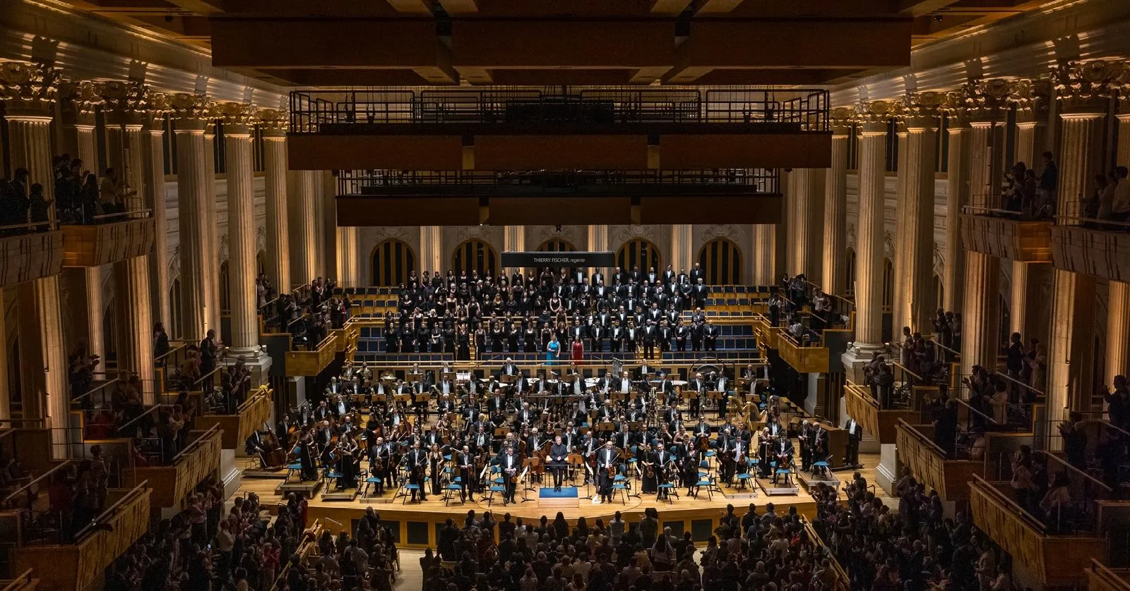 A imagem mostra a Orquestra e o Coro no palco da Sala São Paulo.