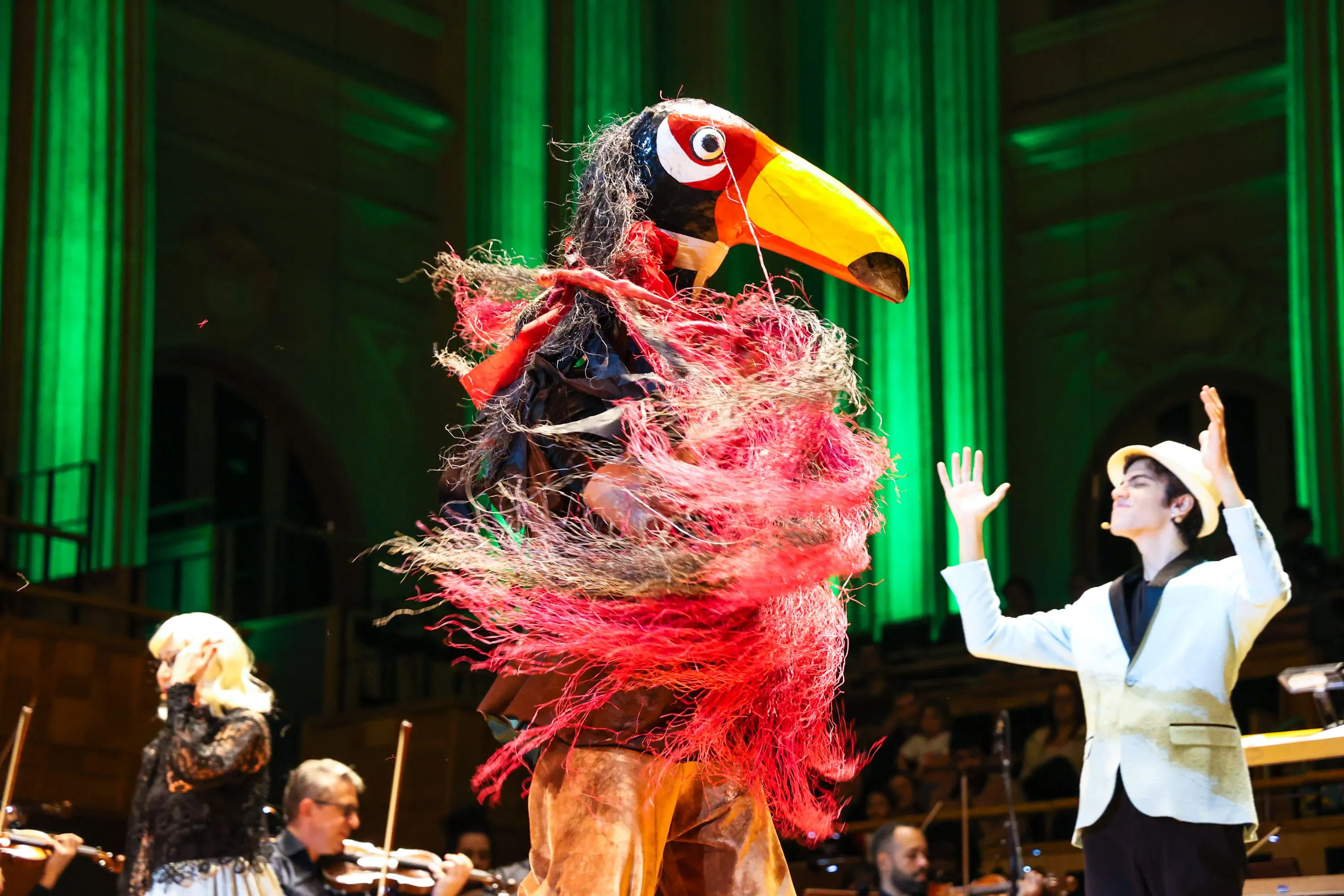 Imagem amarela vibrante, dentro dela, está escrito "tucca" em azul e "música pela cura" em branco,
