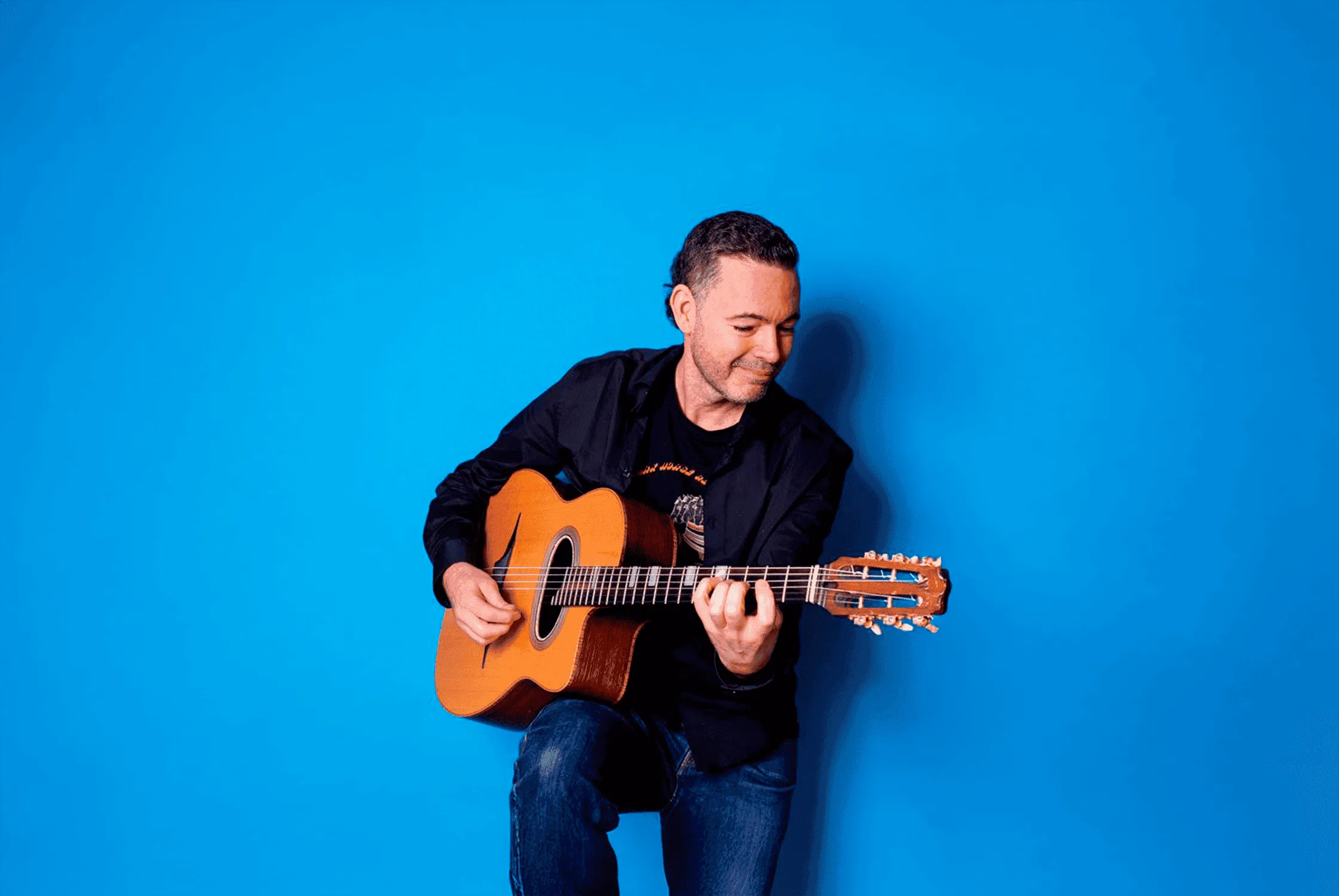 Robin Nolan com guitarra em fundo azul.