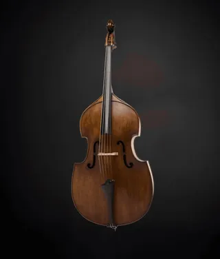 Jefferson Collacico is a white man with brown hair and a mustache. He is wearing a black T-shirt and holding a double bass.