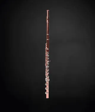 Savio Araujo is a white man with short gray hair. He is wearing a black shirt and holding the flute close to his chest.