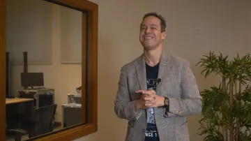 Foto de Leonardo García, homem branco, adulto e de cabelos curtos e pretos. Ele veste blazer cinza acima de uma camiseta preta.