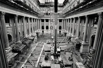 A imagem em preto e branco mostra a atual sala de concertos da Sala São Paulo em construção, com materiais de construção espalhados pelo chão.